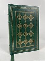 Front cover of the green leather bound book with gold embossed geometric patterns.