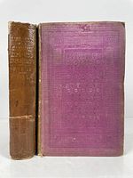 Two antique books side by side showing purple covers heavily faded and spine wear.