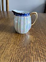 Side view of the small creamer showing opalescent finish with gold accents and scalloped rim