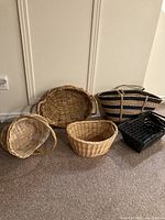 Photo showing five woven baskets and trays of different shapes, sizes, and colors, including a large oval tray with sturdy handles and four various baskets.