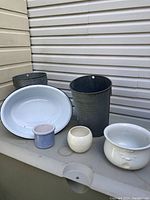 All six items including the oval enamel basin (white with chips), chamber pot missing handle used as a planter, two large galvanized pails, and two small plant pots shown together on a ledge.