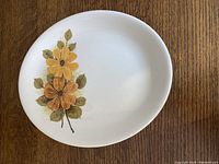 Oval sandstone ironstone platter with yellow and orange flower design on wooden surface, front side visible