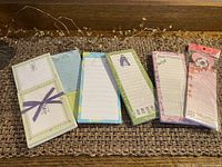 View showing six small notepads in a row, each with different cover designs and colors, placed on a textured brown surface.
