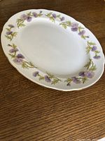 Top view of the porcelain platter showing the oval shape and floral thistle pattern in purple and green around the rim.