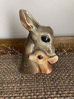 Front view of a glazed ceramic vase shaped like a deer head with a fawn, showing detailed facial features and coloration.