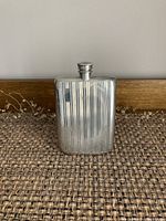 Front view of silver flask standing upright, showing vertical stripe pattern.