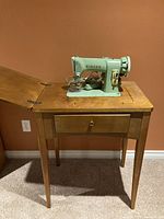 Singer sewing machine mounted in wooden sewing cabinet with drawer, side view showing machine and cabinet details