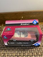 Solido model car in original pink and black packaging, clearly showing the 1:43 metal die-cast Cadillac Biarritz model car inside.