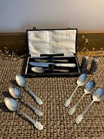Full lot showing six sterling silver spoons with decorative handles from the 1960s alongside child's cutlery set in box and vintage salt and pepper shakers