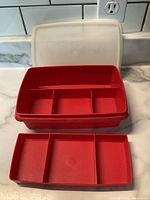 Top image showing open red plastic box with removable tray divided into three compartments and clear lid behind it.