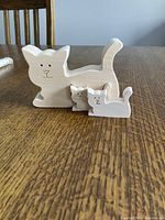 Three-piece wooden cat puzzle displayed separately on wooden table.