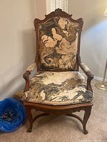 Front view of the vintage armchair showing detailed carving on the wooden frame and marbled upholstery.