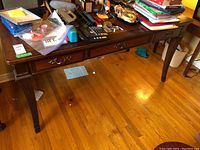 Full frontal photo of the wood desk showing the surface clutter and pullout keyboard drawer beneath.