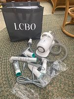 Full lot view showing vacuum base, hose, grooming attachments, and LCBO tote bag