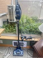 Full upright vacuum with handheld unit attached and two additional nozzle attachments on the floor.