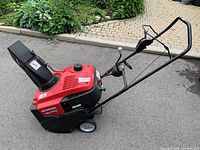 Front-side view of red Honda HS720 showing intake housing, chute and control levers