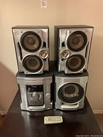 Full stereo system including two speakers, central unit, subwoofer, and remote control on floor