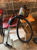 Two vacuum cleaners shown: Bissell AeroSwift Compact and Dirt Devil Quick Flip Plus. Bissell vacuum's clear dirt canister and stick vacuum's hose are visible.