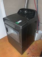 Dark gray Whirlpool Cabrio front-load dryer with a windowed door, control dial and buttons visible on top panel.