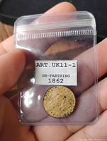 Front side of the 1862 gold gilt farthing coin showing Queen Victoria profile inside a transparent plastic holder with label