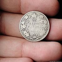 Reverse side of 1914 Canadian 25 cent silver coin showing crown, denomination, Canada text, year and maple leaf wreath.
