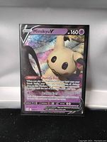 Photo of Mimikyu V holo foil Pokemon card with holographic effects and details visible.