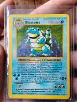 Blastoise Pokémon card front showing holographic image and card text with scratches and wear.