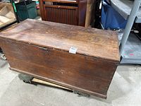 Closed view of the antique wooden foot locker chest showing the top and sides with visible wood grain and patina.
