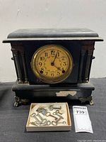 Front view of the antique mantle clock showing dial and skeleton keys lying in a box in front of it.