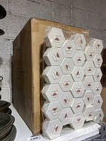 Side view of the shrink-wrapped stack of hexagon-shaped jewelry boxes on pallet, showing multiple rows of boxes with Moricci logo.