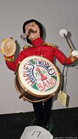 Byers Choice One Man Band caroler figurine, front view showing red jacket, drum with 'Harvey Twiddles Band' text, and tambourine with mallet.