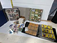 Wide view of two binders filled with sports trading cards and loose cards in front and to the side.