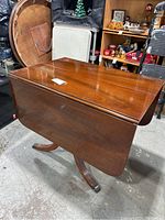 Wood drop leaf table shown with both side leaves folded down, showcasing compact form and polished wood surface.