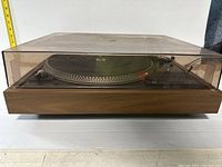 Side view of the Dual 506 turntable with closed dust cover, showing wooden base and controls beneath platter.