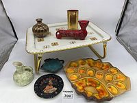 Full view of the lot with TV tray, ceramic dishes including the deviled egg plate, decorative items including signed red cat figurine, small vase, and Las Vegas souvenir plate.