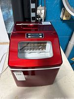 Front view of red ice maker showing clear window and overall design.