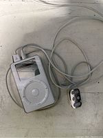 Front view of white Apple iPod with remote control and wired headphones showing device screen and click wheel layout.