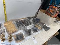 Top view of spread out Mega Bloks pieces and parts in plastic bags along with beige building plates.