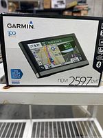 Front of the box showing Garmin Nuvi 2597LMT GPS navigation system and highlighting features like free lifetime maps and traffic.