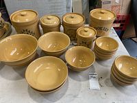 Overview photo showing yellow Pfaltzgraff crocks of varying sizes and nested bowls on white table