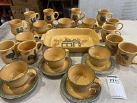 Overall group of 12 mugs and casserole dish on table.