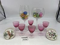 Full lot showing six pink cordial glasses, two large stemmed glasses holding miniature Christmas balls, and two botanical trinket dishes.