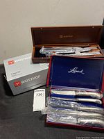 Wusthof knife set in wooden box and Leonard set of knives in a blue box, both photographed with original packaging boxes.