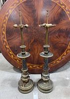 Pair of tall vintage brass and ceramic lamps against a decorative wood background