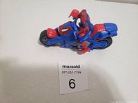 Blue and red motorcycle toy with Spider-Man figure mounted on it, shown from the left side.