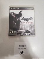 Photo of the Batman Arkham City PlayStation 3 game case showing cover art with Batman crouched over Gotham City.