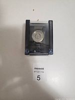 Front view of the Harry Potter watch inside a clear plastic display box showing the Hogwarts crest on the dial.