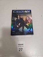 Photo of the front of the CSI NY Complete First Season DVD box set showing holographic cover and two lead characters.
