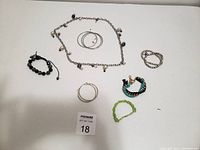 Image showing various jewelry items laid out on white surface including bracelets, hoop earrings, and a necklace