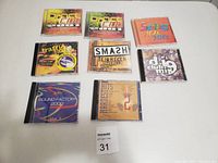 Nine dance music CDs arranged on a white surface, all with colorful and stylized covers indicating various dance/electronic music compilations.